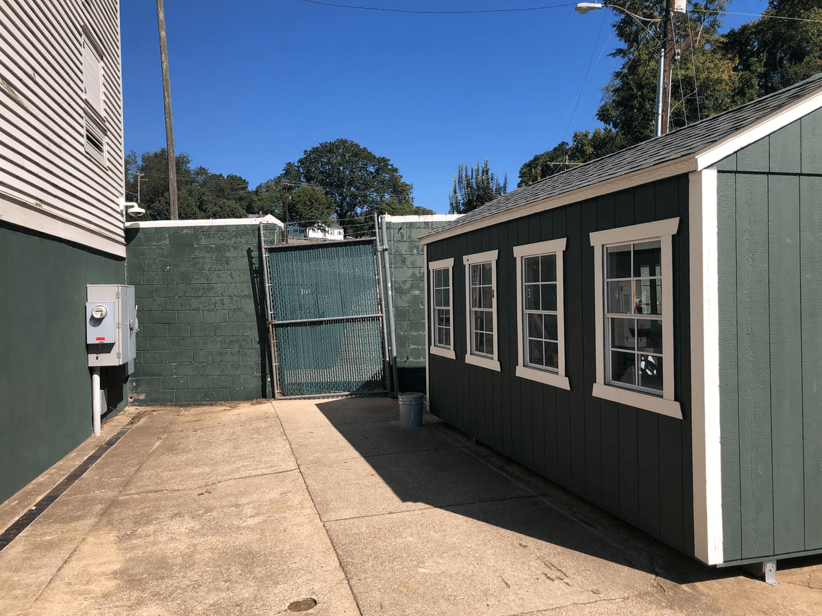 Green shed behind fenced courtyard